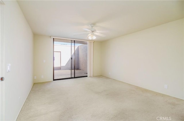 carpeted empty room featuring ceiling fan and expansive windows