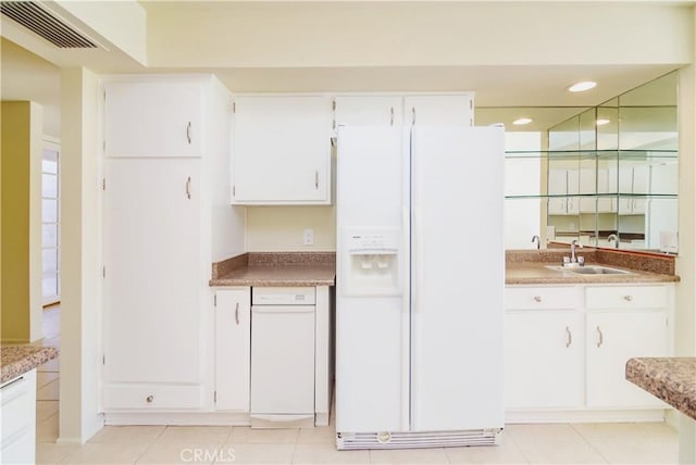 kitchen with light tile patterned floors, sink, white fridge with ice dispenser, and white cabinets