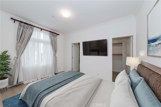 bedroom with hardwood / wood-style floors, a spacious closet, a closet, and ornamental molding