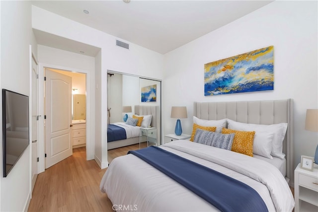 bedroom with ensuite bath, light hardwood / wood-style floors, and a closet