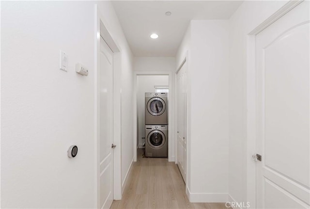 clothes washing area featuring stacked washer / dryer and light hardwood / wood-style flooring