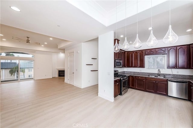 kitchen featuring a raised ceiling, sink, light hardwood / wood-style flooring, appliances with stainless steel finishes, and decorative light fixtures