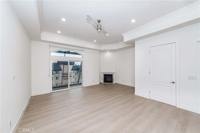 unfurnished living room with ornamental molding, a tray ceiling, and light hardwood / wood-style flooring