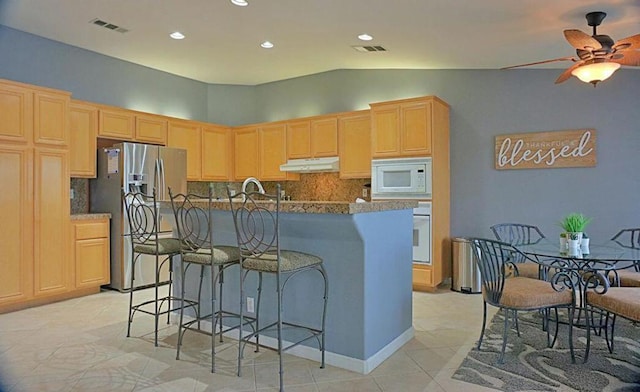 kitchen featuring light brown cabinetry, tasteful backsplash, white appliances, ceiling fan, and lofted ceiling