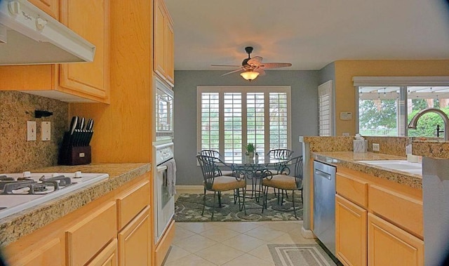 kitchen with light brown cabinetry, stainless steel appliances, and ceiling fan