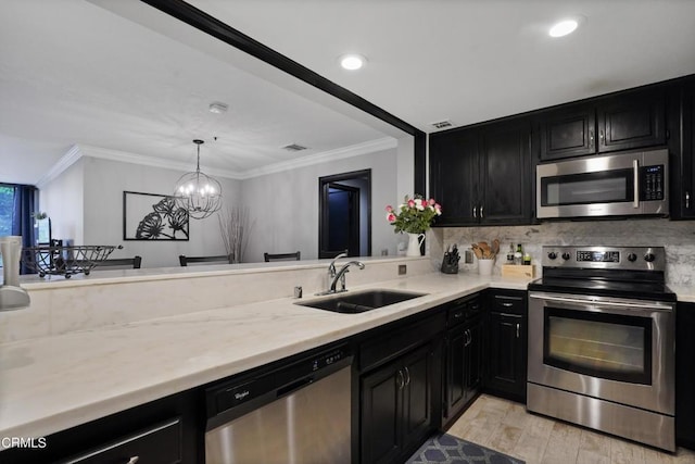 kitchen featuring appliances with stainless steel finishes, sink, decorative light fixtures, light hardwood / wood-style flooring, and a chandelier