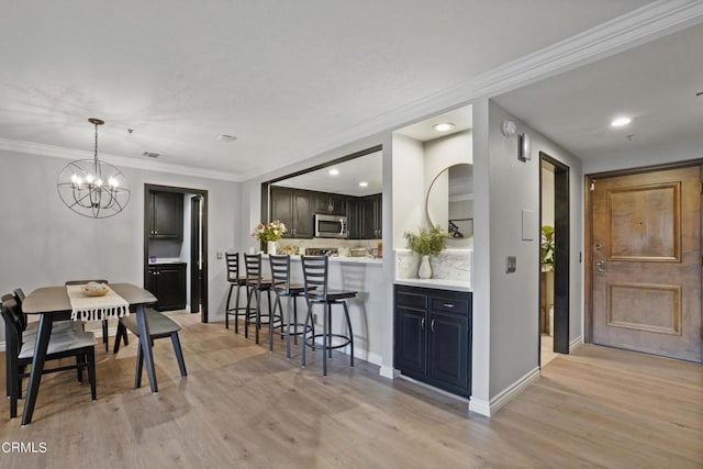 kitchen featuring a chandelier, light wood-type flooring, decorative backsplash, a breakfast bar, and ornamental molding