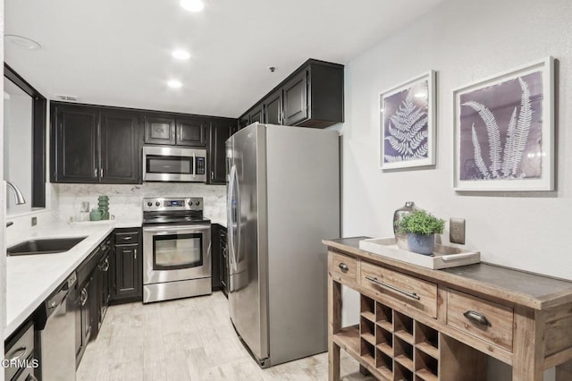 kitchen featuring decorative backsplash, sink, appliances with stainless steel finishes, and light hardwood / wood-style flooring