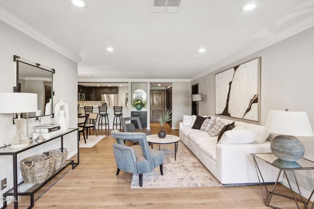 living room with light wood-type flooring and ornamental molding