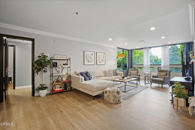 living room with crown molding, light hardwood / wood-style floors, and a wall of windows