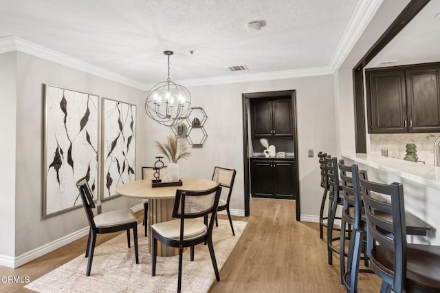 dining area with a chandelier, light hardwood / wood-style floors, and crown molding