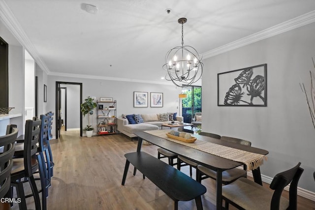 dining space featuring light wood-type flooring, crown molding, and a chandelier