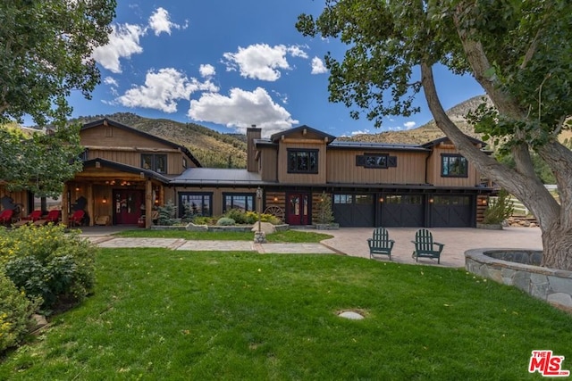 rear view of property with a mountain view, a yard, and a garage