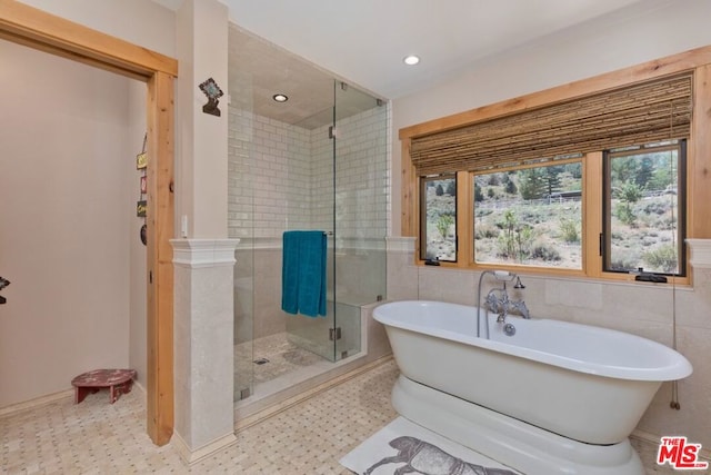 bathroom featuring plus walk in shower and tile walls