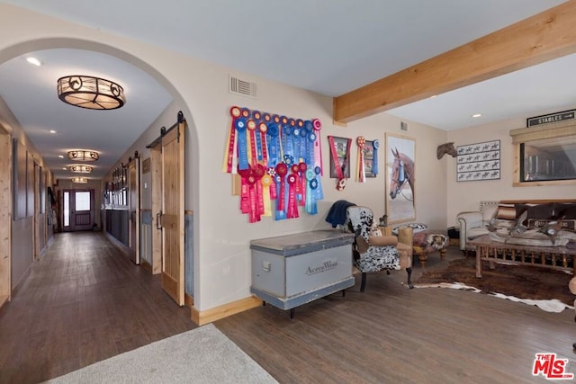 interior space with beamed ceiling, dark hardwood / wood-style floors, and a barn door