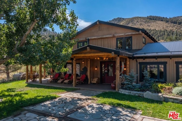 view of front of home with a mountain view, a patio area, and a front lawn