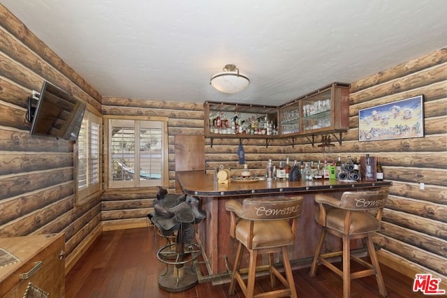 bar with dark hardwood / wood-style floors and rustic walls