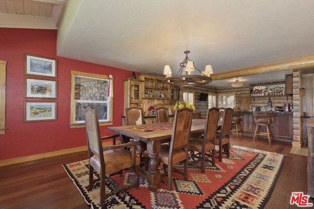 dining room with vaulted ceiling with beams, dark hardwood / wood-style floors, and a chandelier