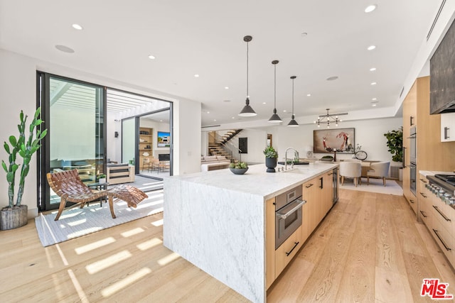 kitchen featuring a large island, pendant lighting, double oven, light hardwood / wood-style floors, and light brown cabinetry