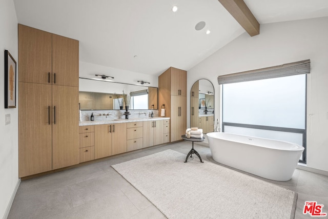 bathroom with backsplash, vanity, a bathing tub, and vaulted ceiling with beams