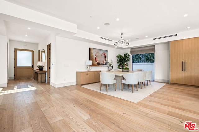 unfurnished dining area with a barn door, a chandelier, and light wood-type flooring