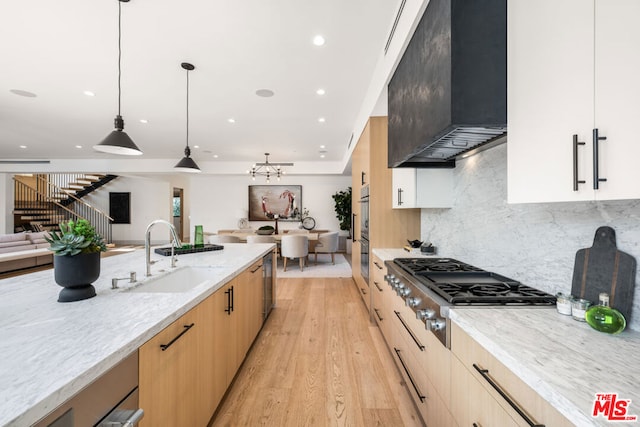 kitchen featuring sink, hanging light fixtures, light stone counters, stainless steel appliances, and custom range hood