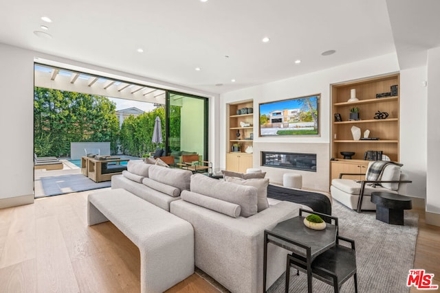 living room featuring built in features and light hardwood / wood-style floors