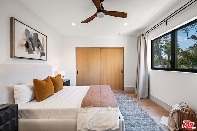 bedroom with light hardwood / wood-style flooring, a closet, and ceiling fan