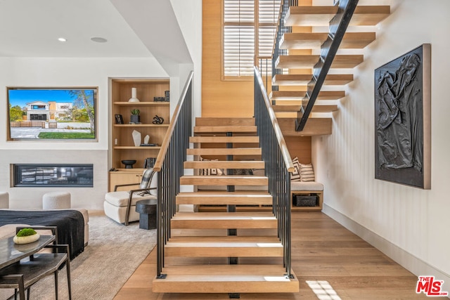 stairway with hardwood / wood-style floors and built in shelves