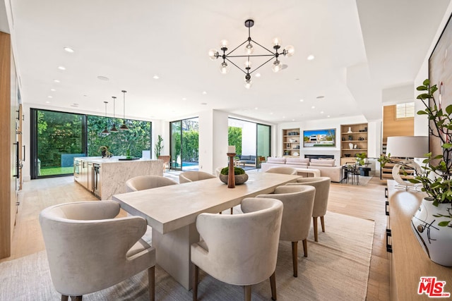 dining room with a notable chandelier, built in features, floor to ceiling windows, and light wood-type flooring