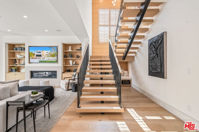 stairway with hardwood / wood-style floors and built in features