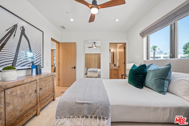 carpeted bedroom with ensuite bathroom and ceiling fan