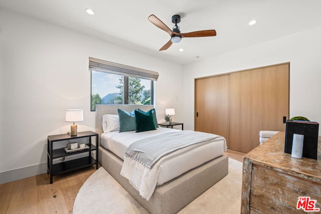 bedroom featuring light hardwood / wood-style floors, a closet, and ceiling fan