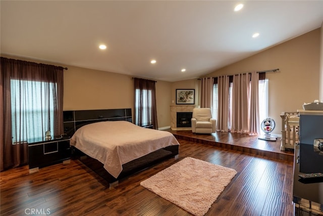 bedroom featuring a tile fireplace, dark hardwood / wood-style floors, and vaulted ceiling