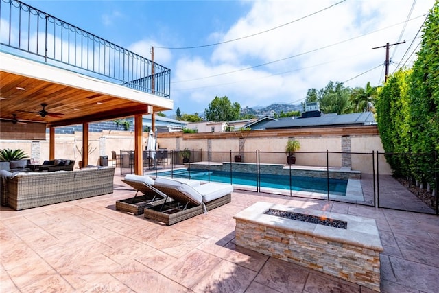 view of swimming pool featuring ceiling fan, a patio, and an outdoor living space with a fire pit