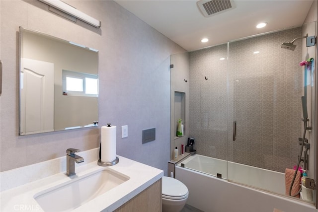 full bathroom featuring vanity, toilet, and bath / shower combo with glass door