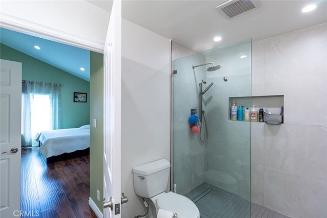 bathroom with hardwood / wood-style floors, toilet, tiled shower, and vaulted ceiling