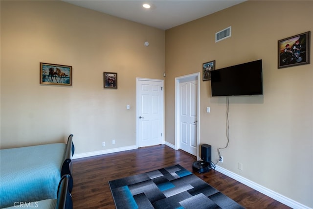 bedroom with a high ceiling and dark hardwood / wood-style floors