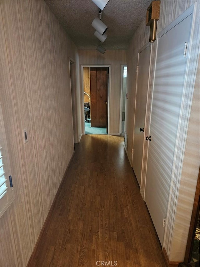 corridor with a textured ceiling and hardwood / wood-style floors