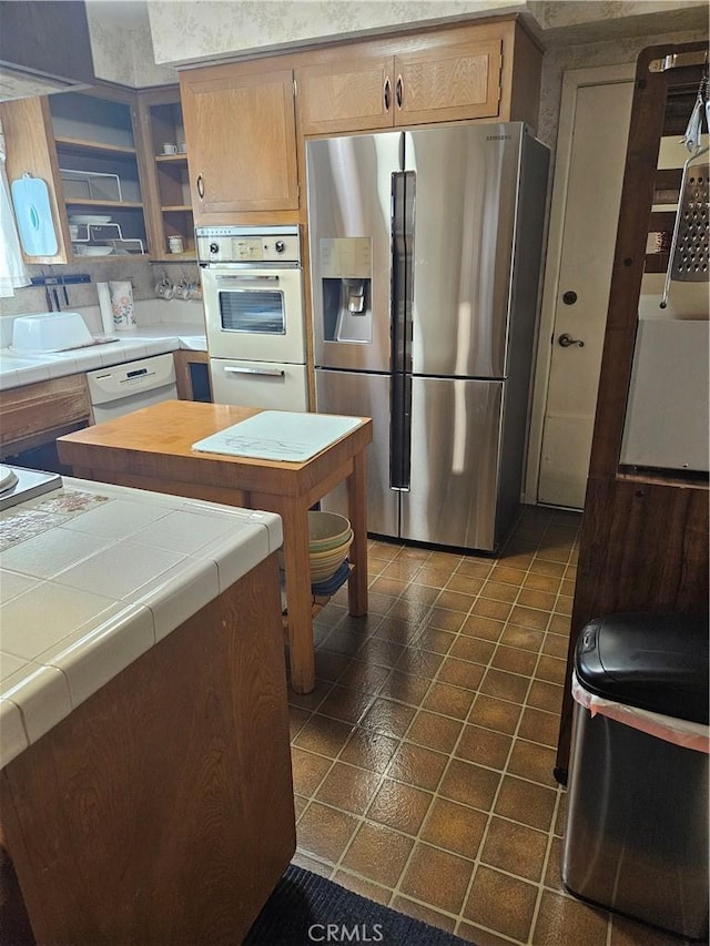 kitchen with dishwasher, stainless steel fridge, tile countertops, and dark tile patterned flooring