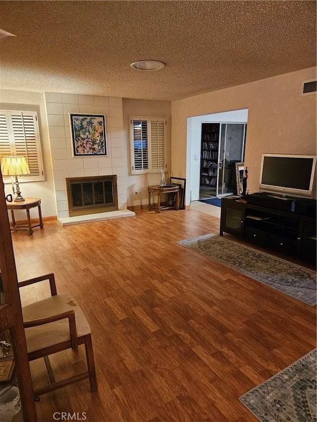 living room with hardwood / wood-style flooring, a textured ceiling, and a fireplace