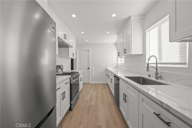 kitchen featuring light hardwood / wood-style floors, sink, white cabinetry, light stone countertops, and appliances with stainless steel finishes