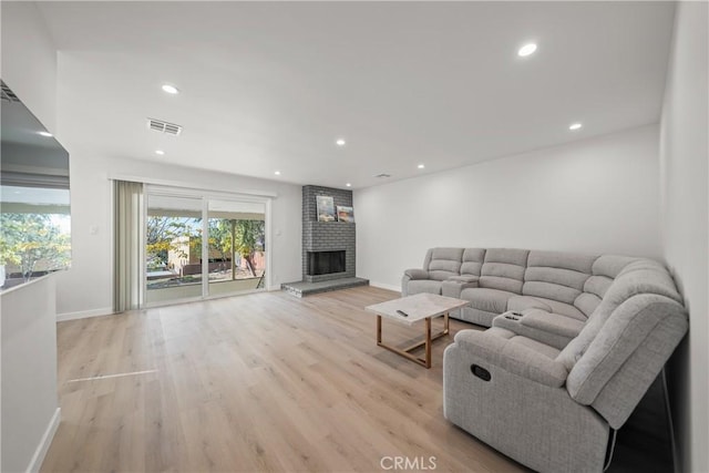 living room featuring a brick fireplace and light hardwood / wood-style floors