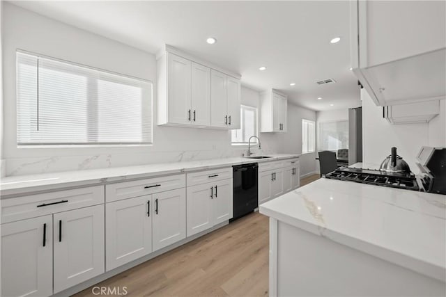 kitchen featuring light stone countertops, dishwasher, white cabinetry, sink, and light hardwood / wood-style flooring