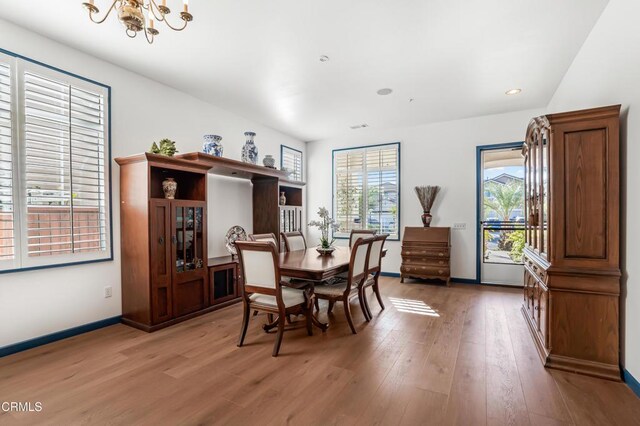 dining space featuring hardwood / wood-style flooring and an inviting chandelier