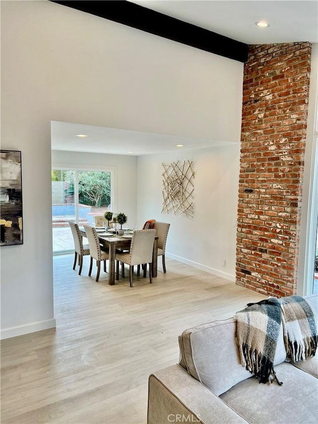 dining room featuring lofted ceiling with beams and light hardwood / wood-style floors