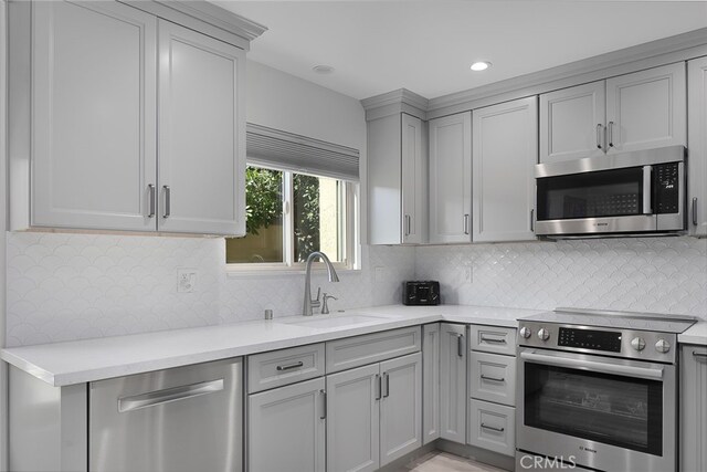 kitchen with light stone counters, sink, backsplash, and appliances with stainless steel finishes