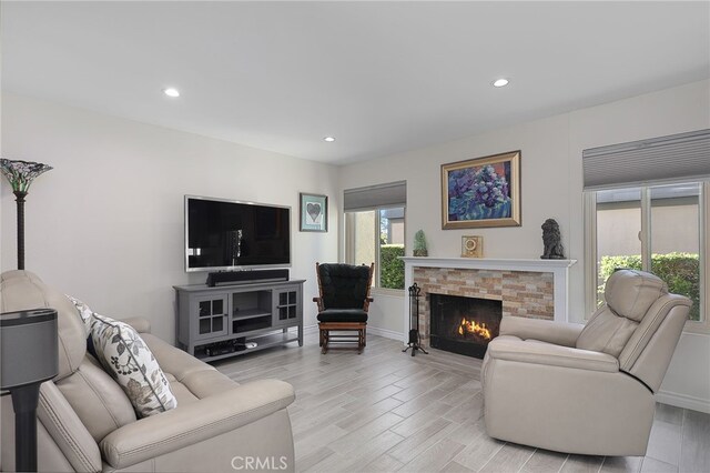 living room with a stone fireplace and light wood-type flooring