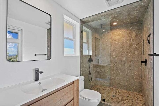 bathroom featuring tiled shower, vanity, and toilet