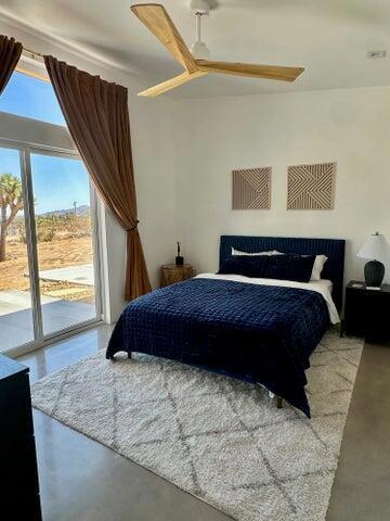 bedroom featuring ceiling fan, access to outside, and concrete flooring